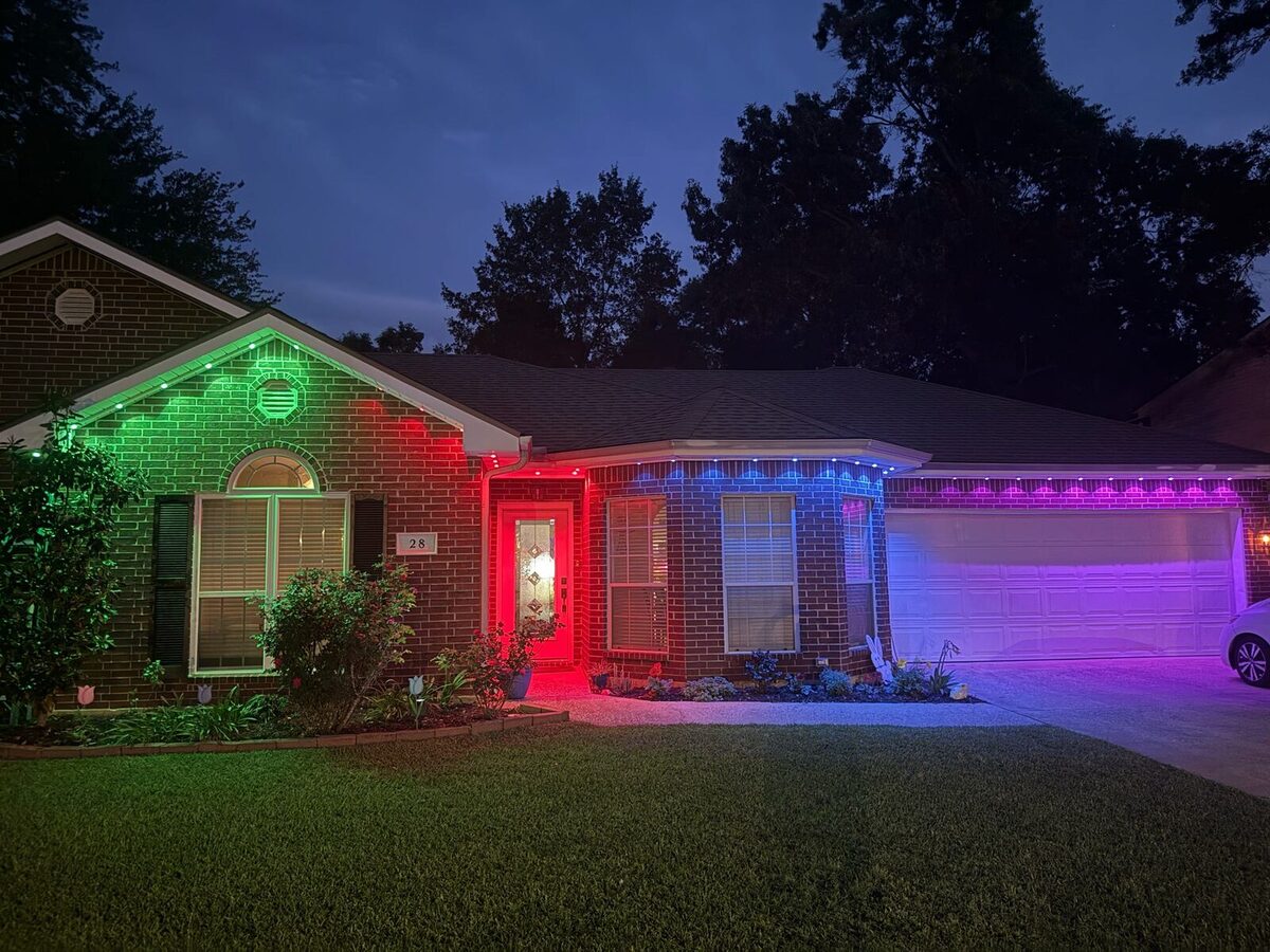 The same home at night with each zone lit a different color — green, red, blue, purple